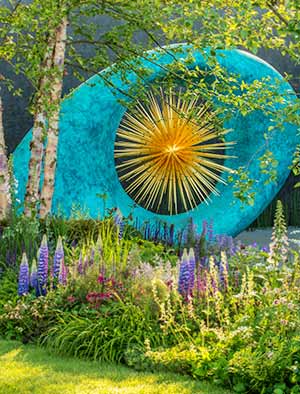 Aeon monumental sculpture set against delicate, pretty planting