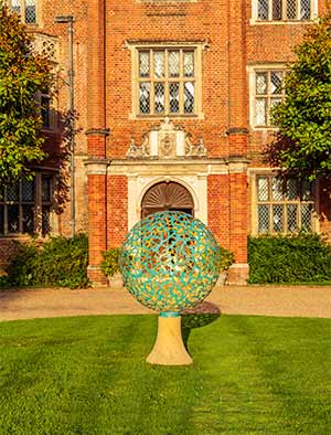 Geminus making a strong formal artistic statement on a pedestal in front of a classic historic house