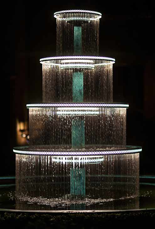 Tall garden fountain dramatically lit at night with LED lighting