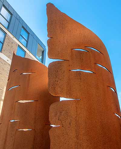 Sculpture of six curved sheets of oxidised steel shaped to look like a pen nib at the top