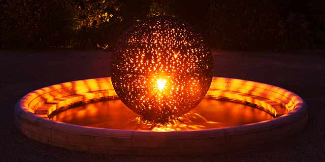 Gold leaf surfaces of the Eclipse sculpture glitter when lit at night