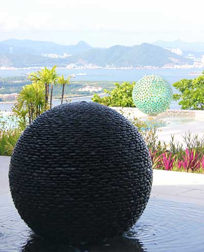 Two different sculptures spheres lined up in front of dramatic bay views
