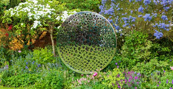 Sculpture made from two parallel circular discs with elaborate laser cut patterns that plays with light and shade