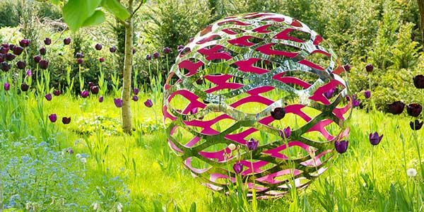 Modern stainless steel sculpture in a beautiful garden setting