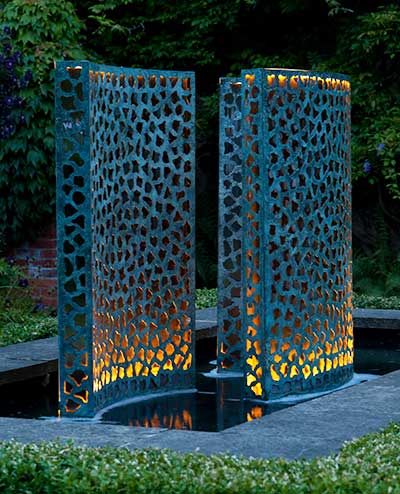 Three verdigris bronze Lattice water walls illuminated at night