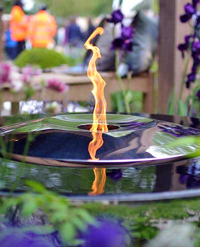 Flame of the Fire Chalice reflected in its water and stainless steel surface