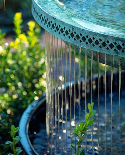 Water falls from the Mimeo Cascade garden fountain in a web of light