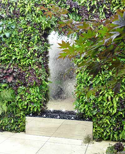 Stainless steel water wall set amidst dense planting