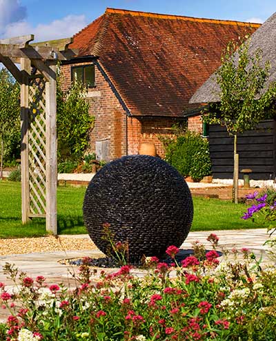 Dark Planet stone water feature in a garden